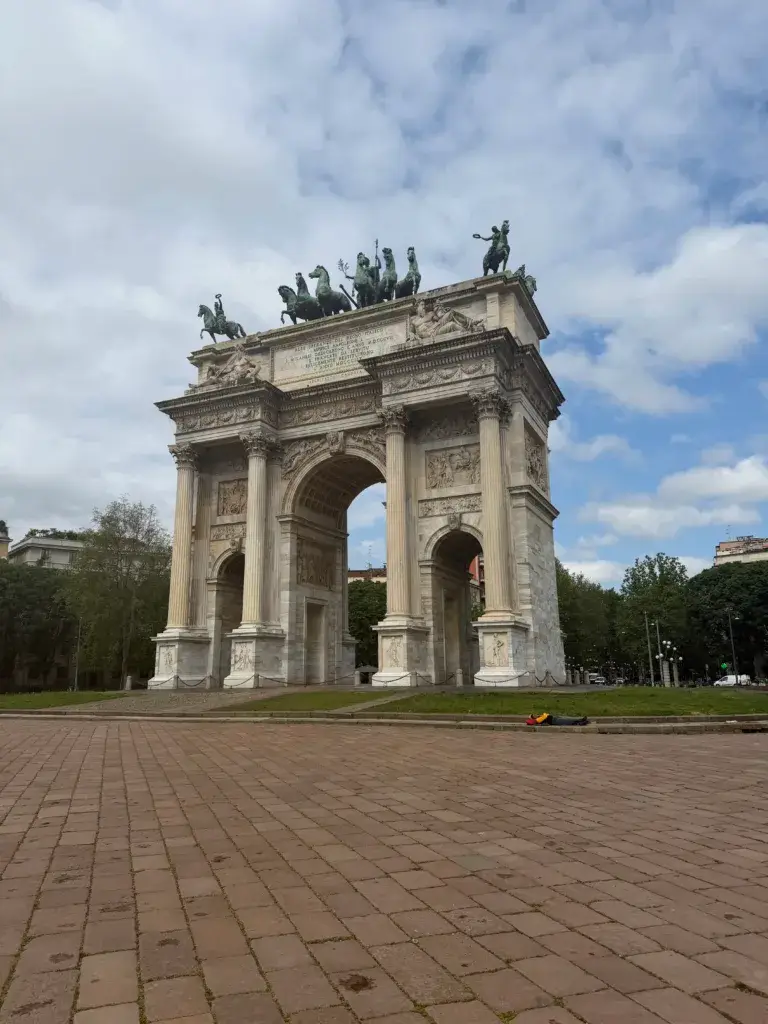 The Arco della Pace neoclassical triumphal arch in Parco Sempione, Milan, with bronze chariot statues against a cloudy sky